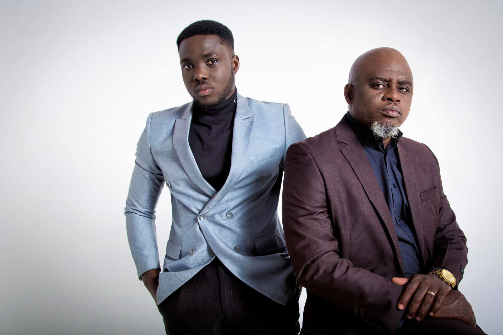 Two men in smart clothes against a pale studio backdrop