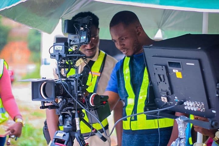 Camera crew in high-visibility vests filming on a road