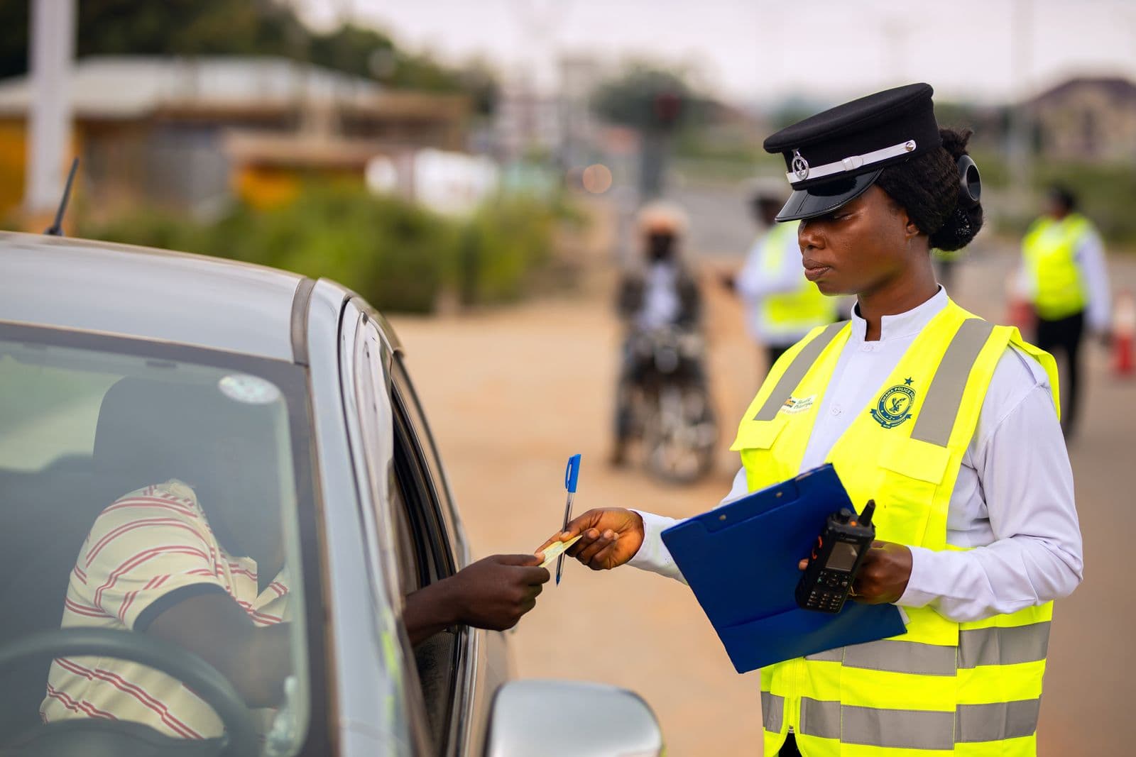 A woman officer in a yellow vest at a car window