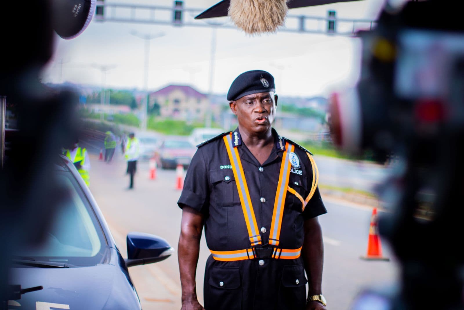 An officer standing beside a car as the crew films
