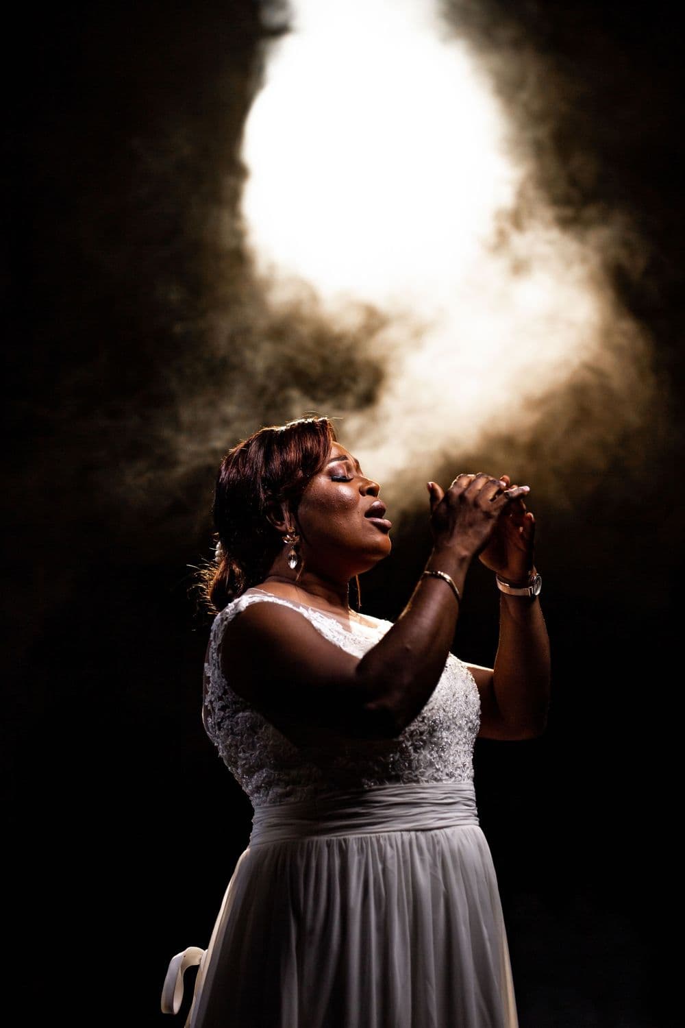 The singer lit by a bright beam through haze