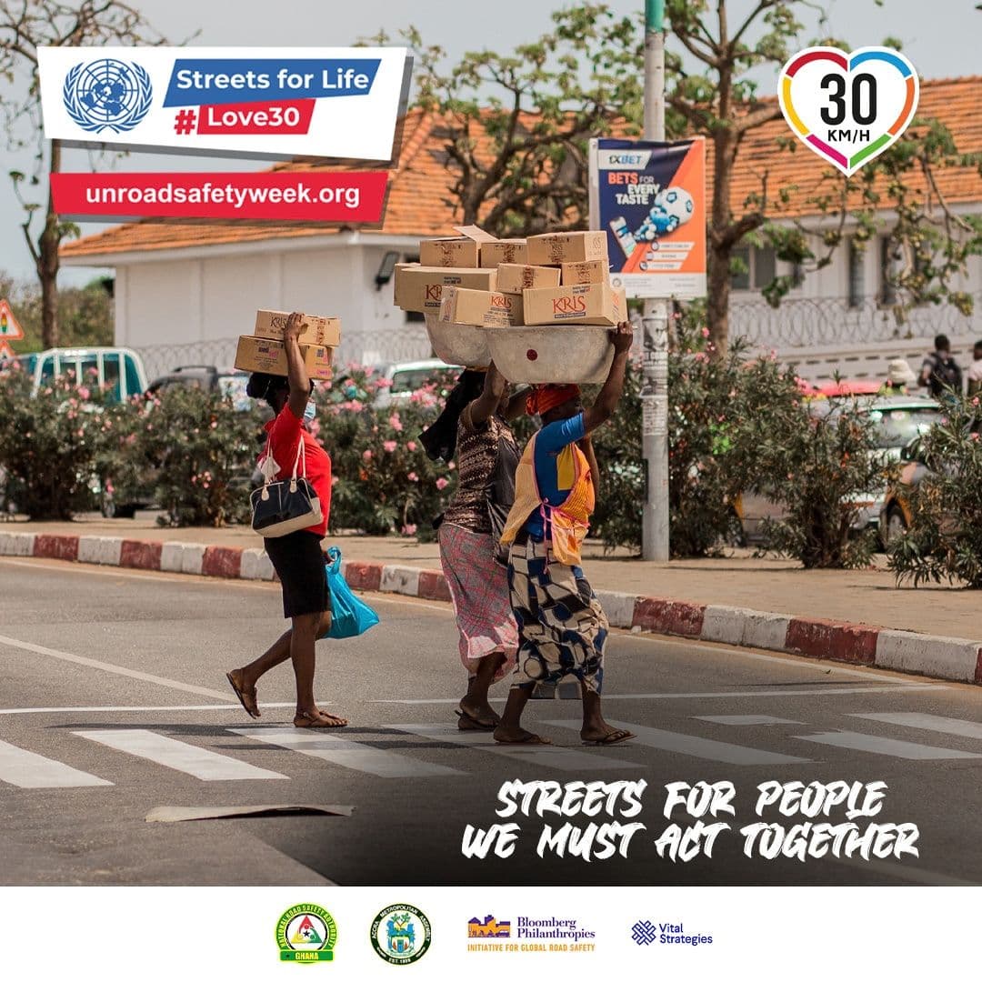 A street scene with people crossing a road and a Streets for People message