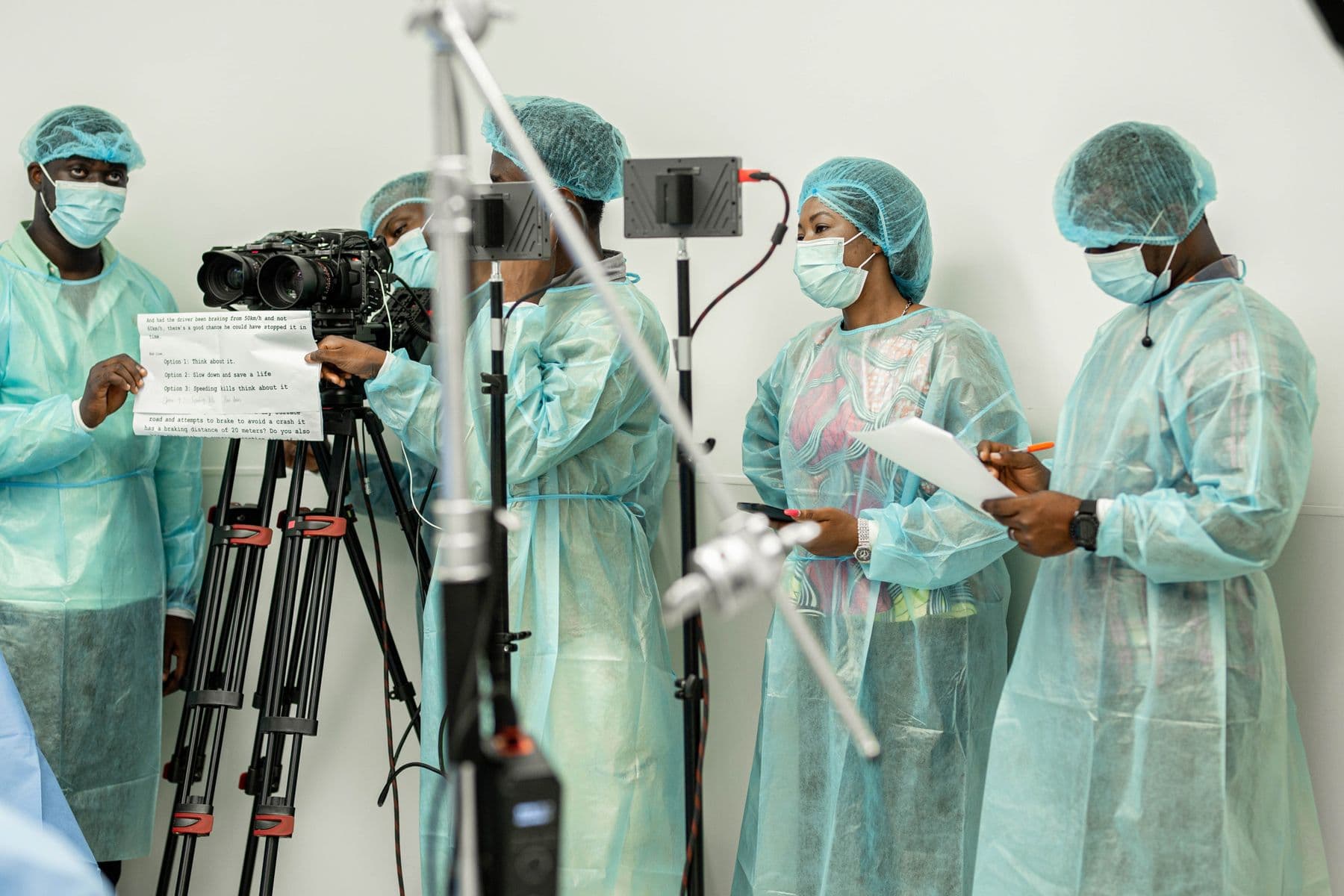 Crew in protective clothing filming with a camera on a tripod