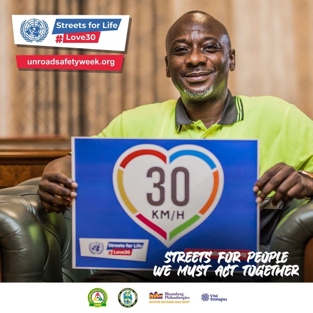 A man seated in an armchair holding a 30 km/h sign
