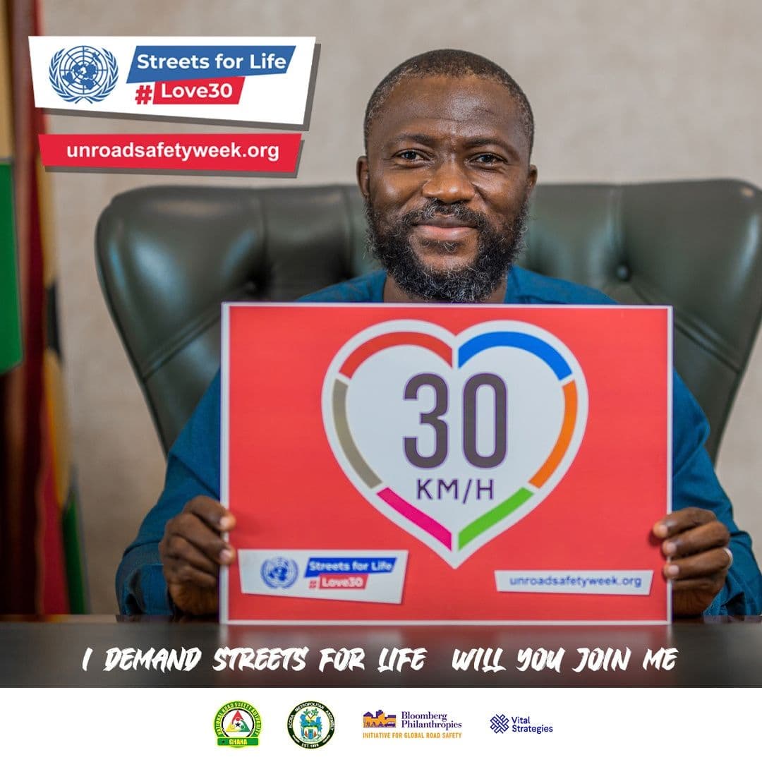 A man in a suit holding a red 30 km/h sign