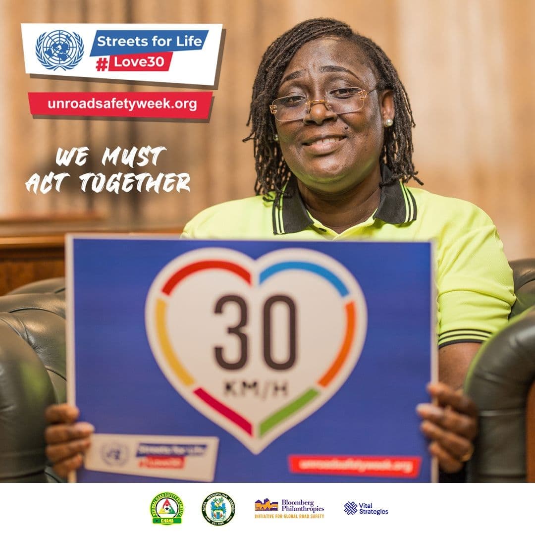 A smiling woman holding a 30 km/h sign
