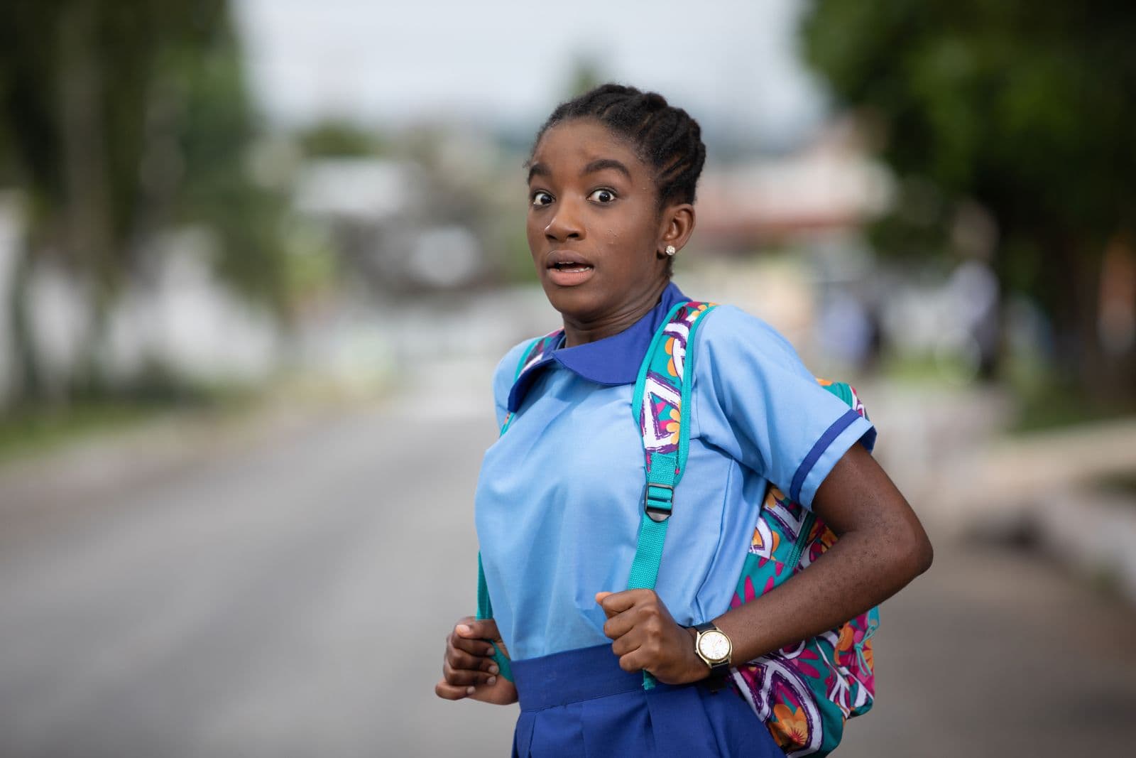 A schoolgirl in uniform and backpack on a quiet road, looking alarmed