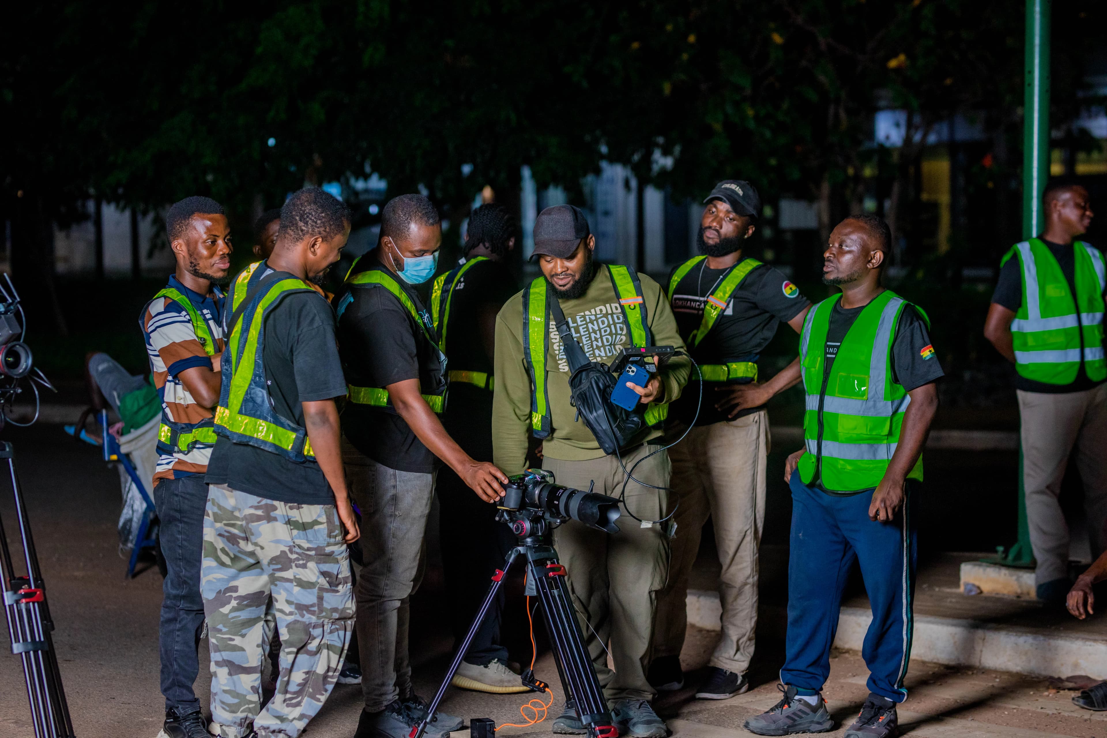 A night shoot on a road beside a speed sign, the crew lit in the dark